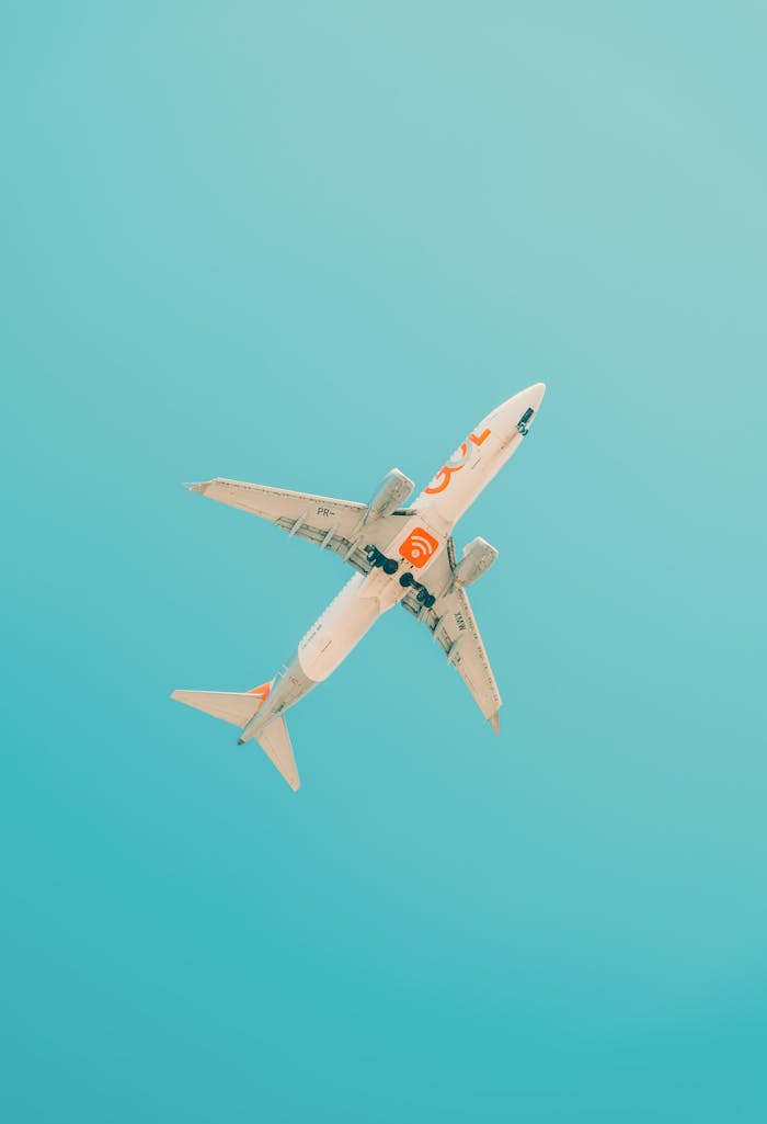 A commercial airplane flies above São Paulo with a clear blue sky, showcasing modern aviation.