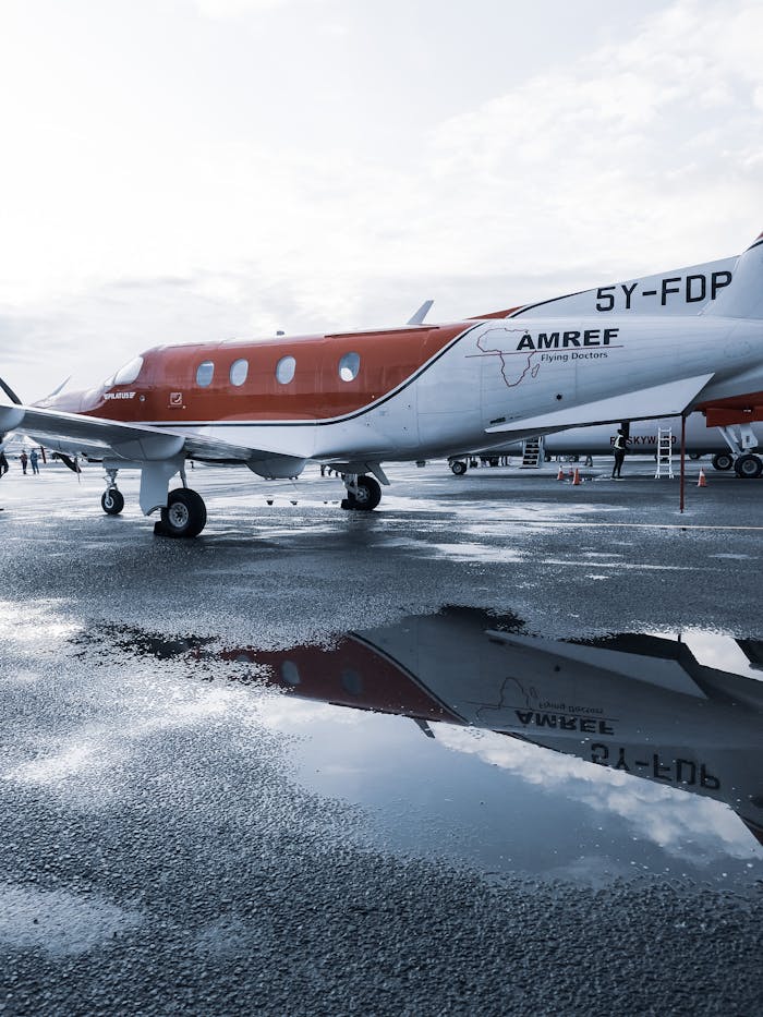 AMREF aircraft parked on a wet tarmac in Kenya, reflecting travel and aviation themes.